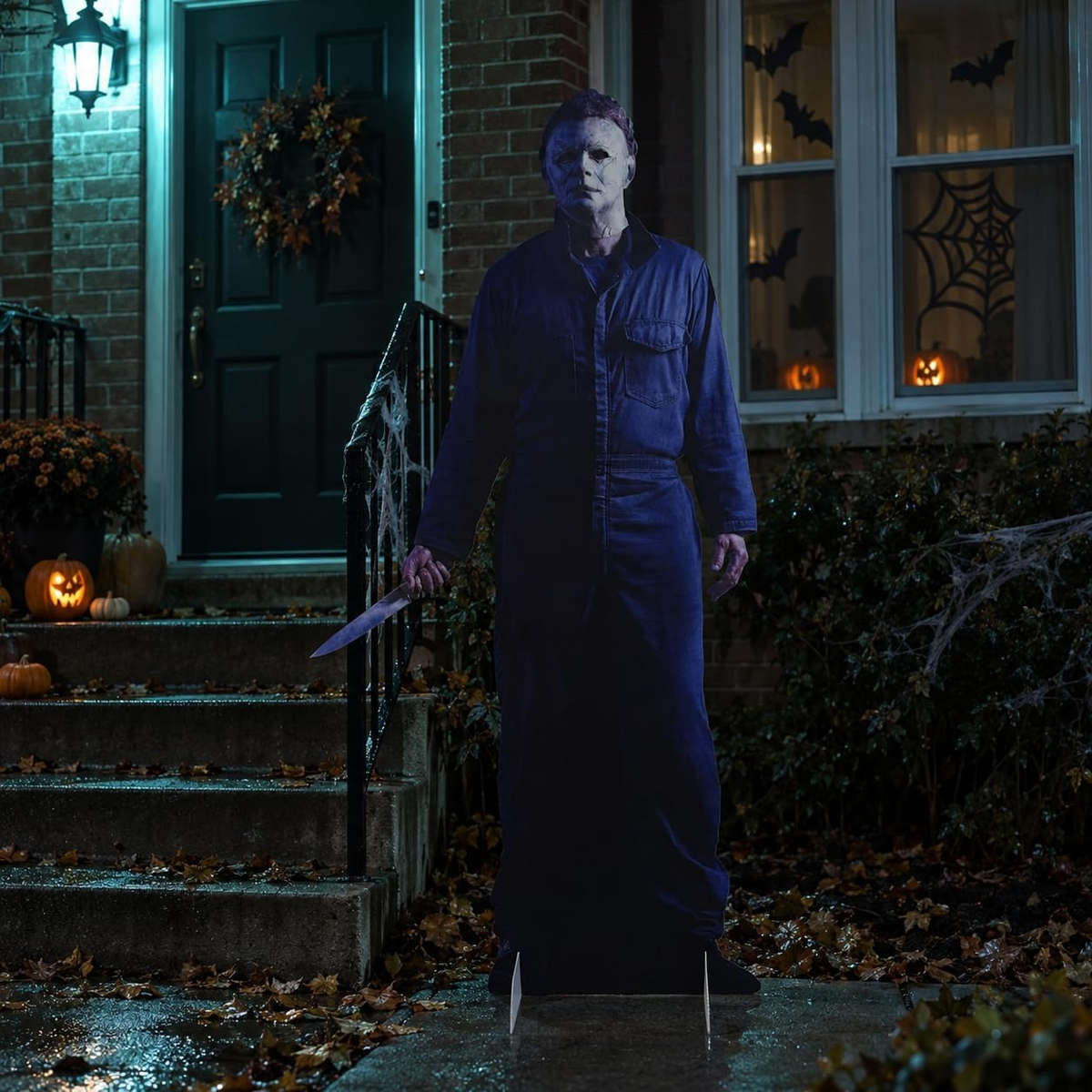 Life-size Michael Myers horror cutout standee by a front door on a Halloween night