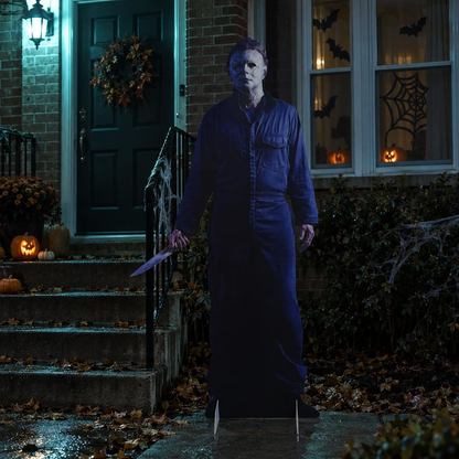 Life-size Michael Myers horror cutout standee by a front door on a Halloween night