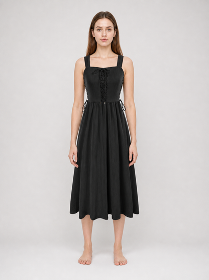 Black midi dress shown full-body on a model, with a fitted lace-up bodice, broad straps, adjustable side ties, and a flared hem