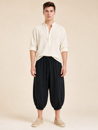 Front view of black cropped pants with a gathered waistband and ankle cuffs, worn with a light shirt