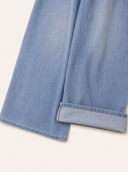 The model features a relaxed style with very wide, full-length legs that create a laid-back silhouette and suit everyday looks. The light blue shade with a subtle denim-like effect makes the piece versatile for warm weather and easy to pair