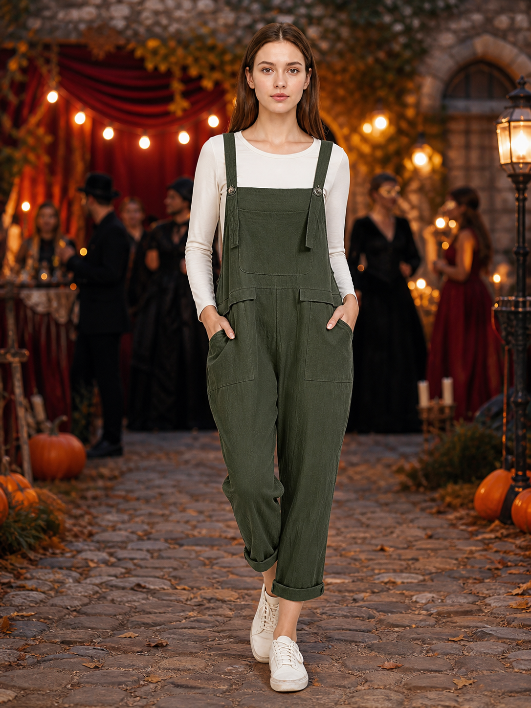Full-body model wearing dark green bib overalls with a chest pocket and side pockets in a warmly lit outdoor evening scene