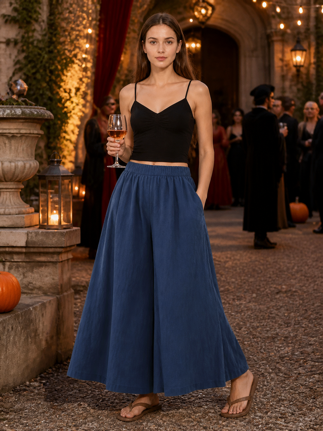 Dark blue wide leg pants with an elastic waistband and side pockets worn with a black camisole at an evening gathering