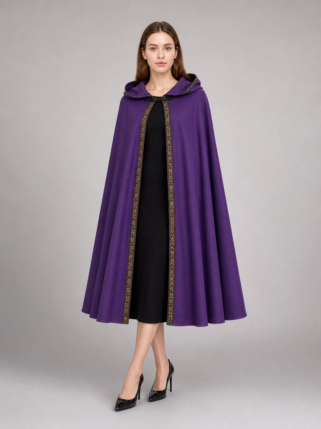 Purple hooded cape with patterned trim, shown on a model over a cream dress