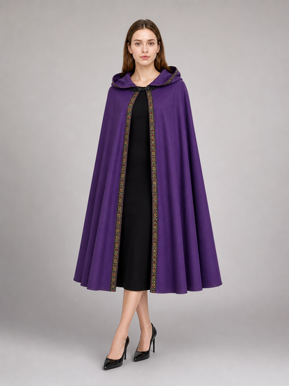 Purple hooded cape with patterned trim, shown on a model over a cream dress