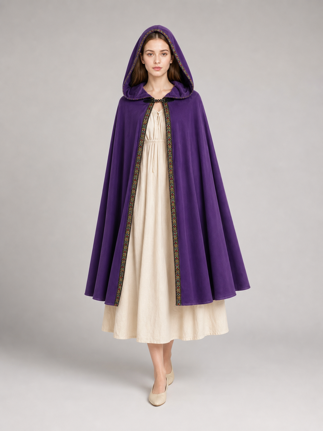Purple hooded cape with patterned trim, shown on a model over a cream dress 2