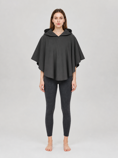 Dark gray hooded poncho with a loose draped fit, shown full-body on a female model in a studio