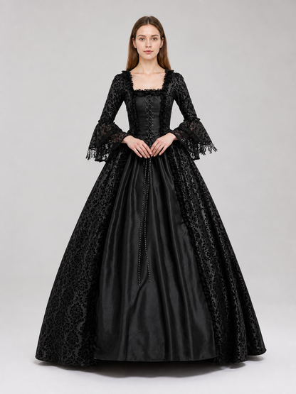 The black dress is designed in the aesthetic of a Victorian-era Gothic costume. The model features a floor-length silhouette, a fitted bodice with a square neckline, and decorative lacing or trim on the front. The long flared sleeves end in