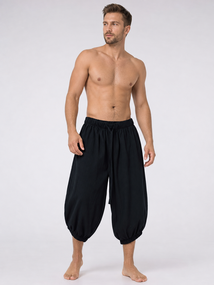 Black cropped pants with an elastic waistband and loose legs, shown full-body on a barefoot shirtless model