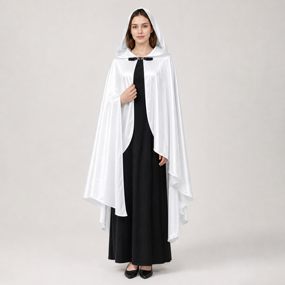 White satin-look hooded cape with flowing layered hem and black toggle closure, modeled full-body over a long black dress