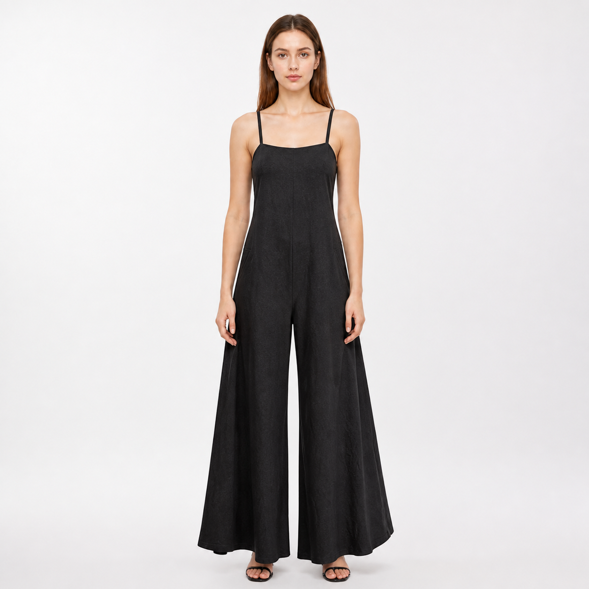Black wide-leg jumpsuit with a straight neckline and thin straps, shown full-body on a model wearing black sandals