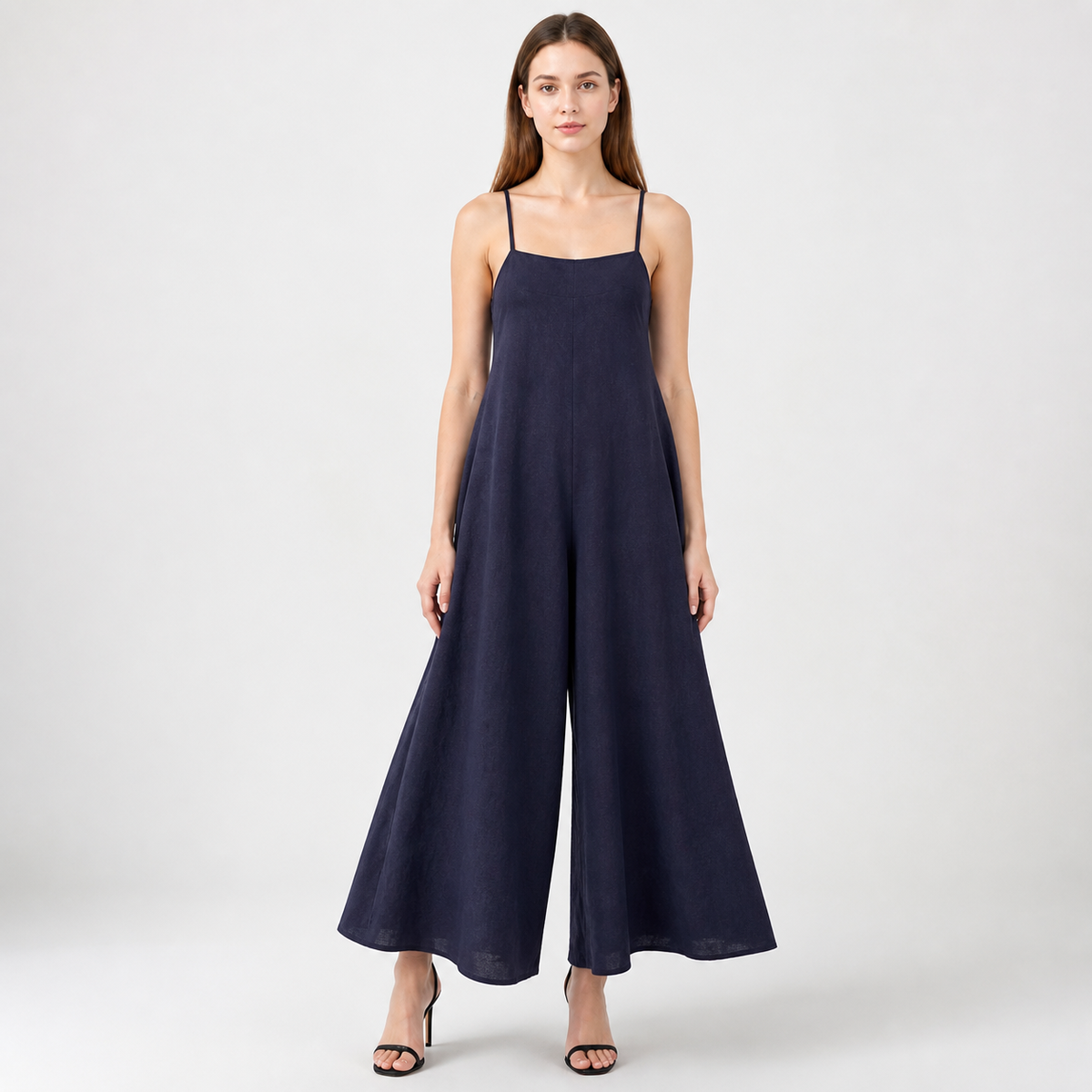 Dark blue wide-leg jumpsuit with thin shoulder straps, modeled full-length against a plain light background