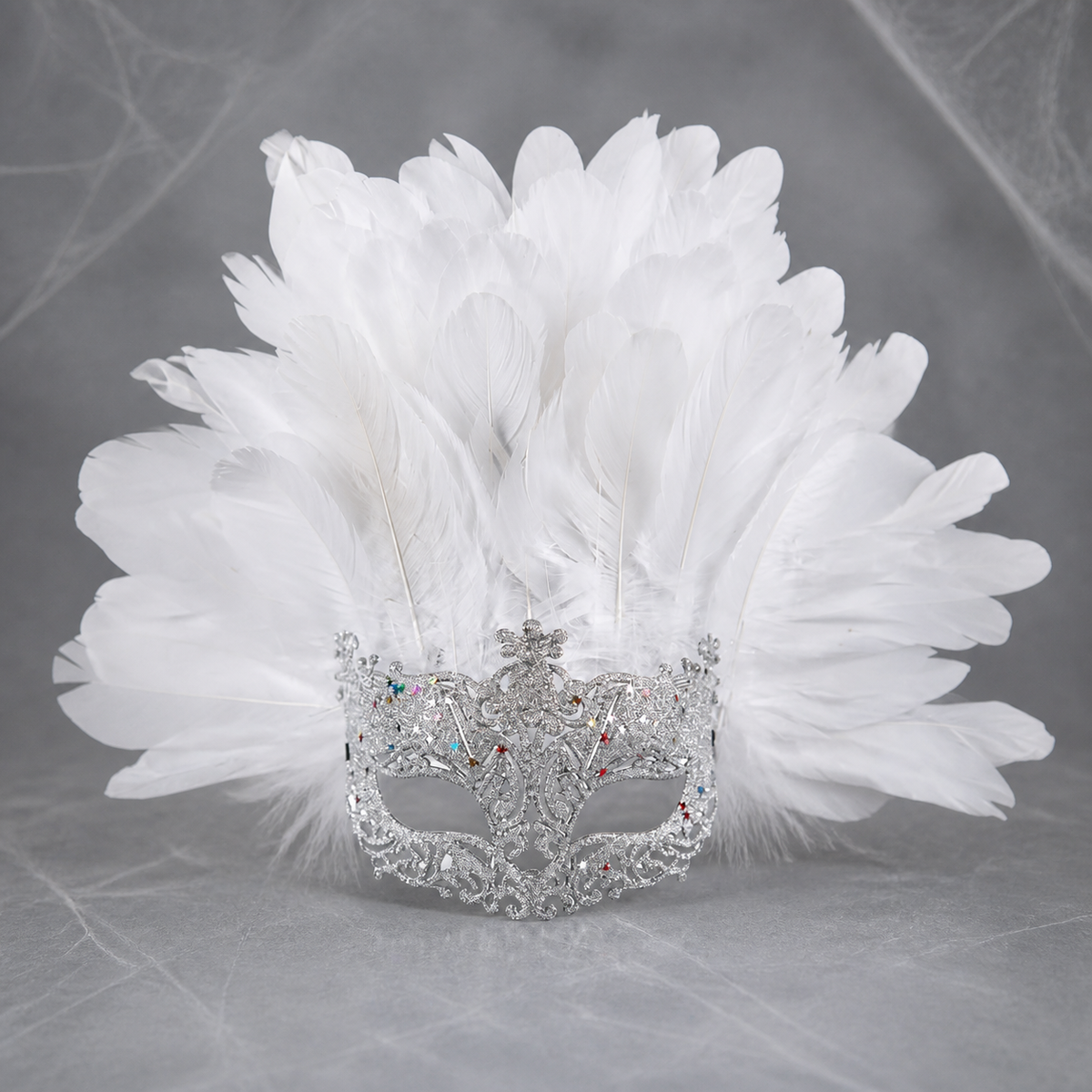 White feather masquerade mask displayed upright against a gray background, showing the ornate silver-tone eye frame
