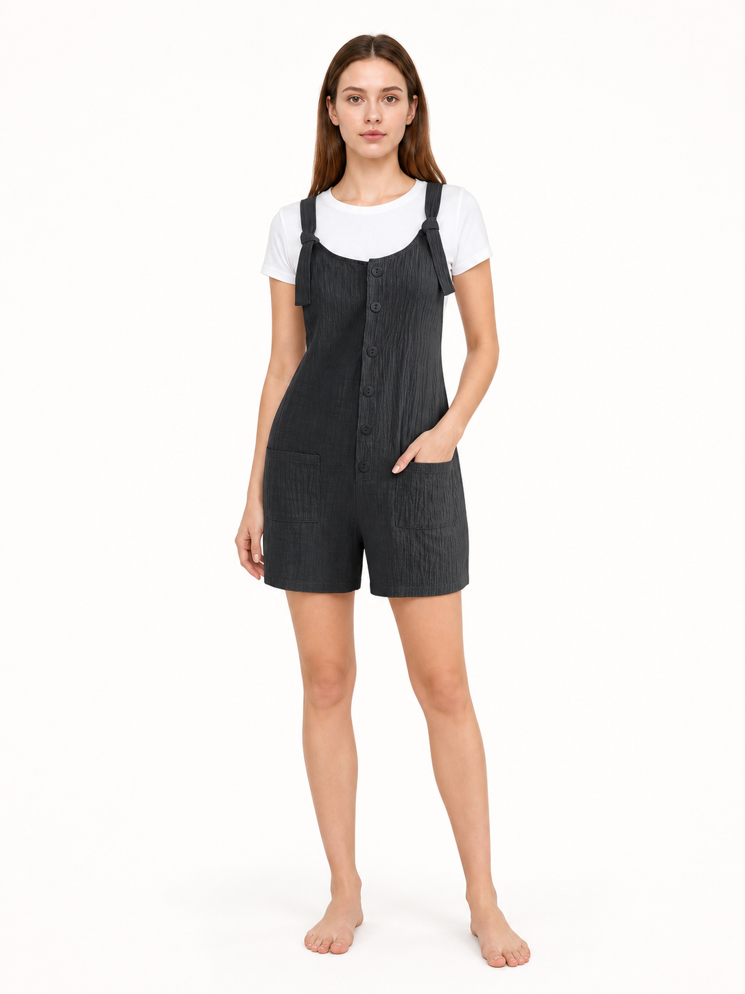 Front view of black textured bib shorts with adjustable straps, button closure, and two pockets on a model