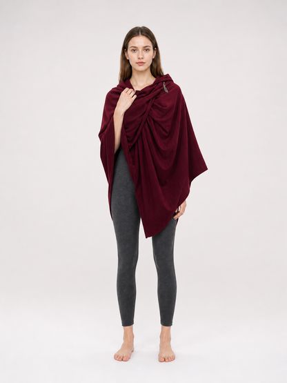 Burgundy hooded cloak with draped front and shoulder fastener, shown on a woman wearing gray leggings in a studio