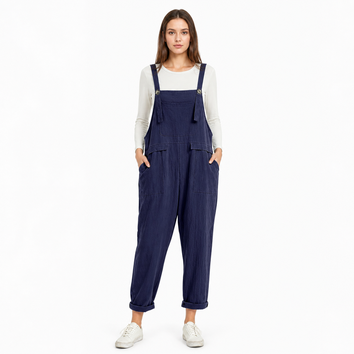 Full-body front view of navy blue bib overalls over a white shirt, showing adjustable shoulder straps, front pockets, and rolled cuffs