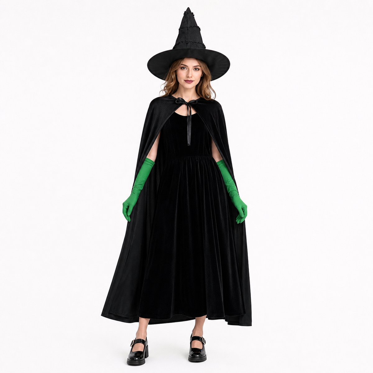 Full-body adult model wearing a black velvet dress and cape with a pointed hat and green gloves