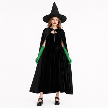 Full-body adult model wearing a black velvet dress and cape with a pointed hat and green gloves