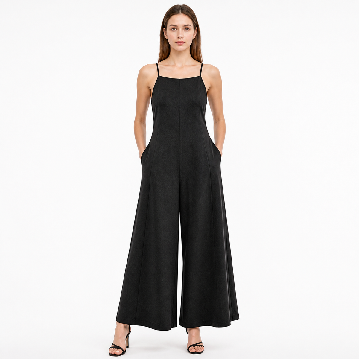 Black wide-leg jumpsuit with thin straps and side pockets, shown full-body on a model wearing black heeled sandals