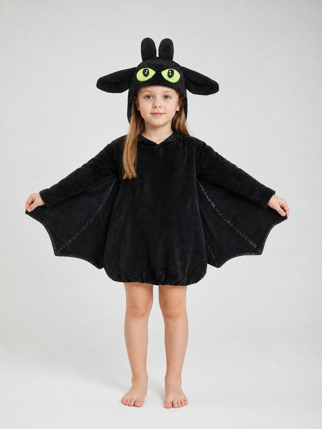 Black plush bat costume shown full-body on a child, with hood, upright ears, large eyes, and extended side wings