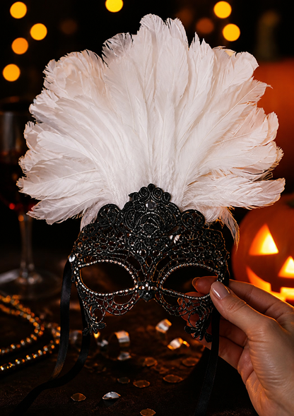 Close-up of a white feather headpiece and black lace mask held in a hand against a dark, warmly lit background