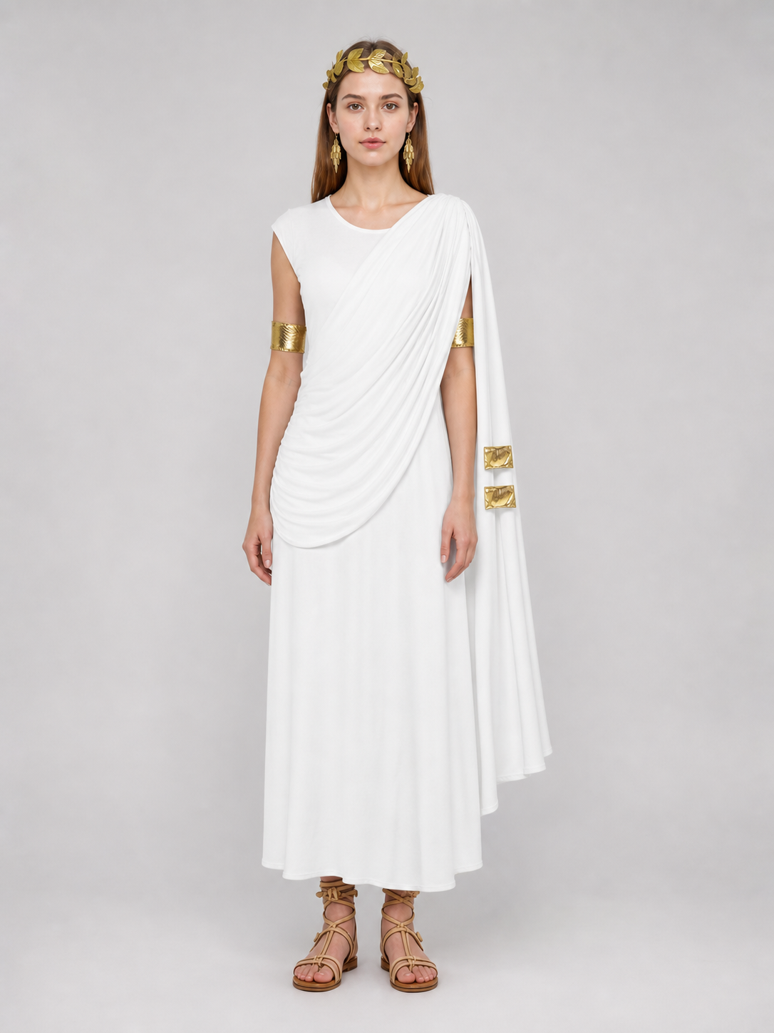 Full-body model wearing a white draped dress with a long flowing train, gold leaf headband, arm bands and flat sandals