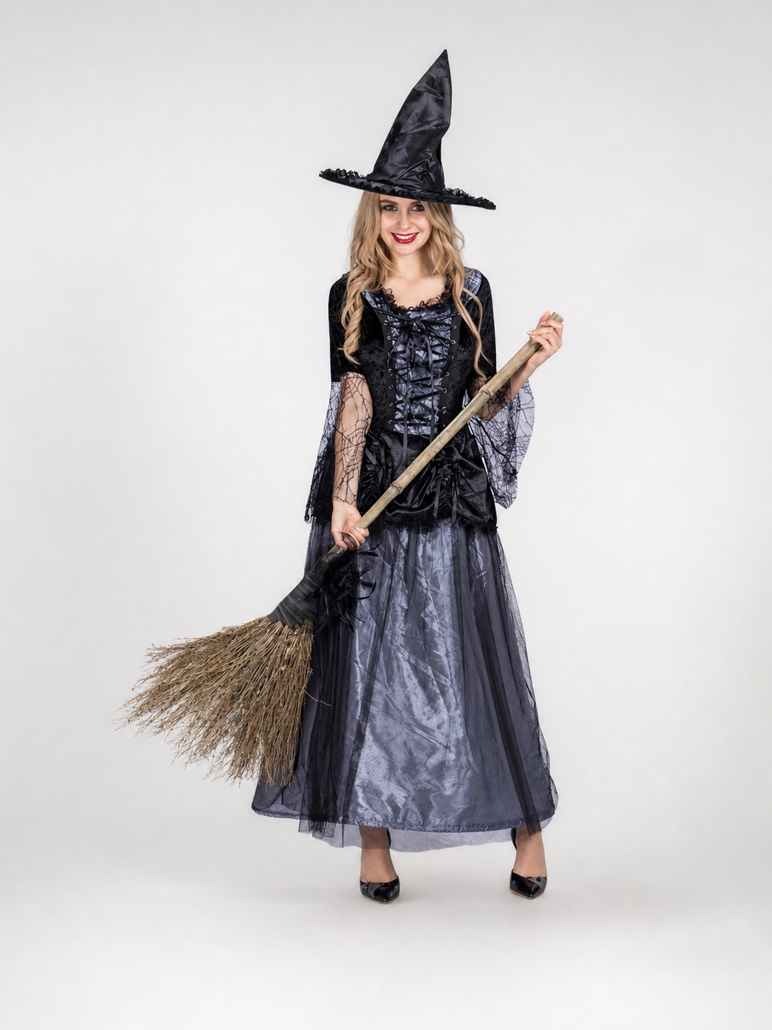 Gothic-style witch costume dress with hat for themed events. The design is mainly black and dark gray, with patterned textured fabric and sheer black accents. The look is centered on a long dress with a fitted lace-up corset, a ruffled neck