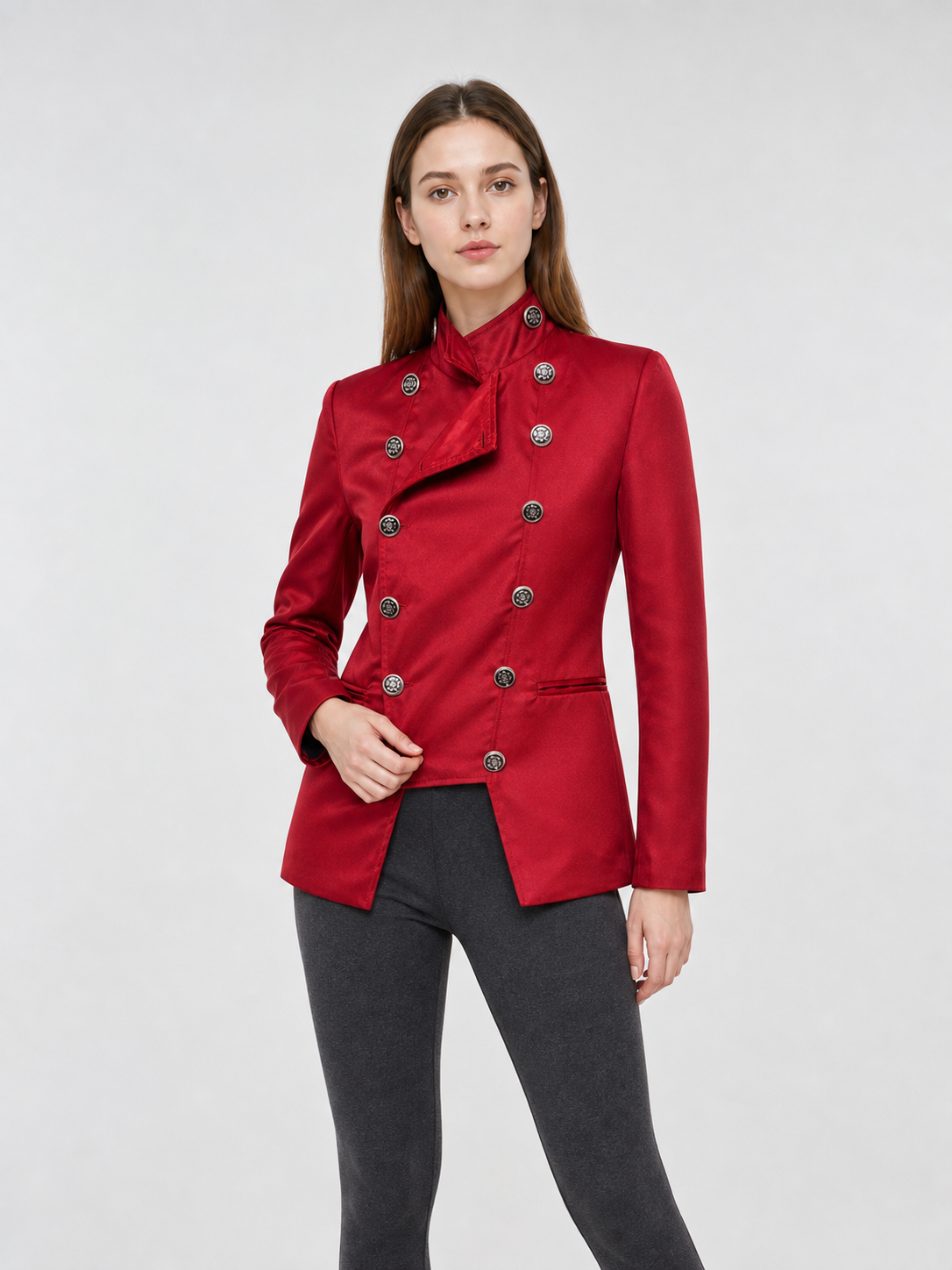 The jacket is presented in a vintage red color and designed in a military style with elements of Gothic aesthetics. The model features a distinctive front construction with a diagonal wrap, giving the garment a bold character. A double row 