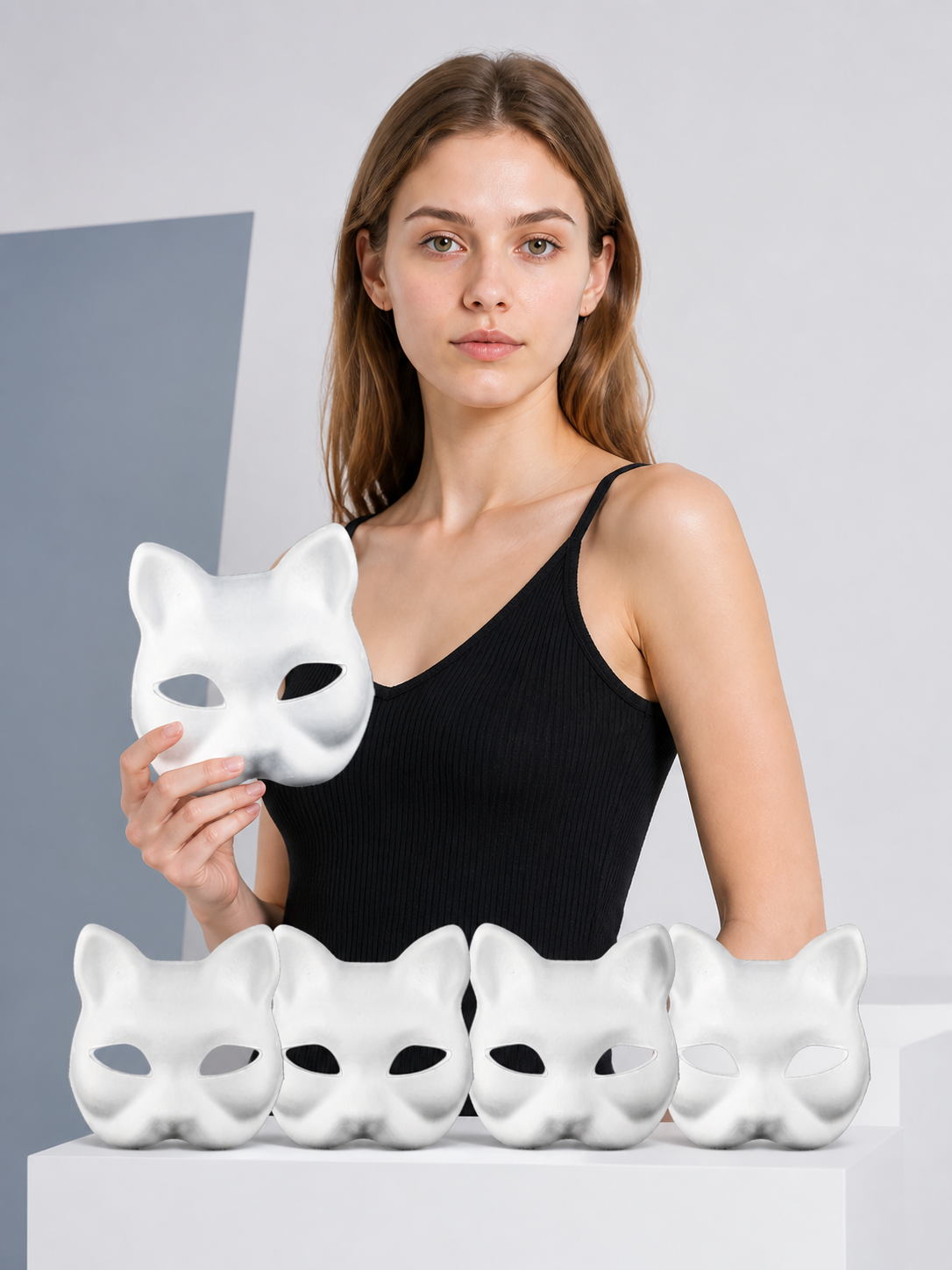 Model holding a white cat mask with four more matching masks on the table