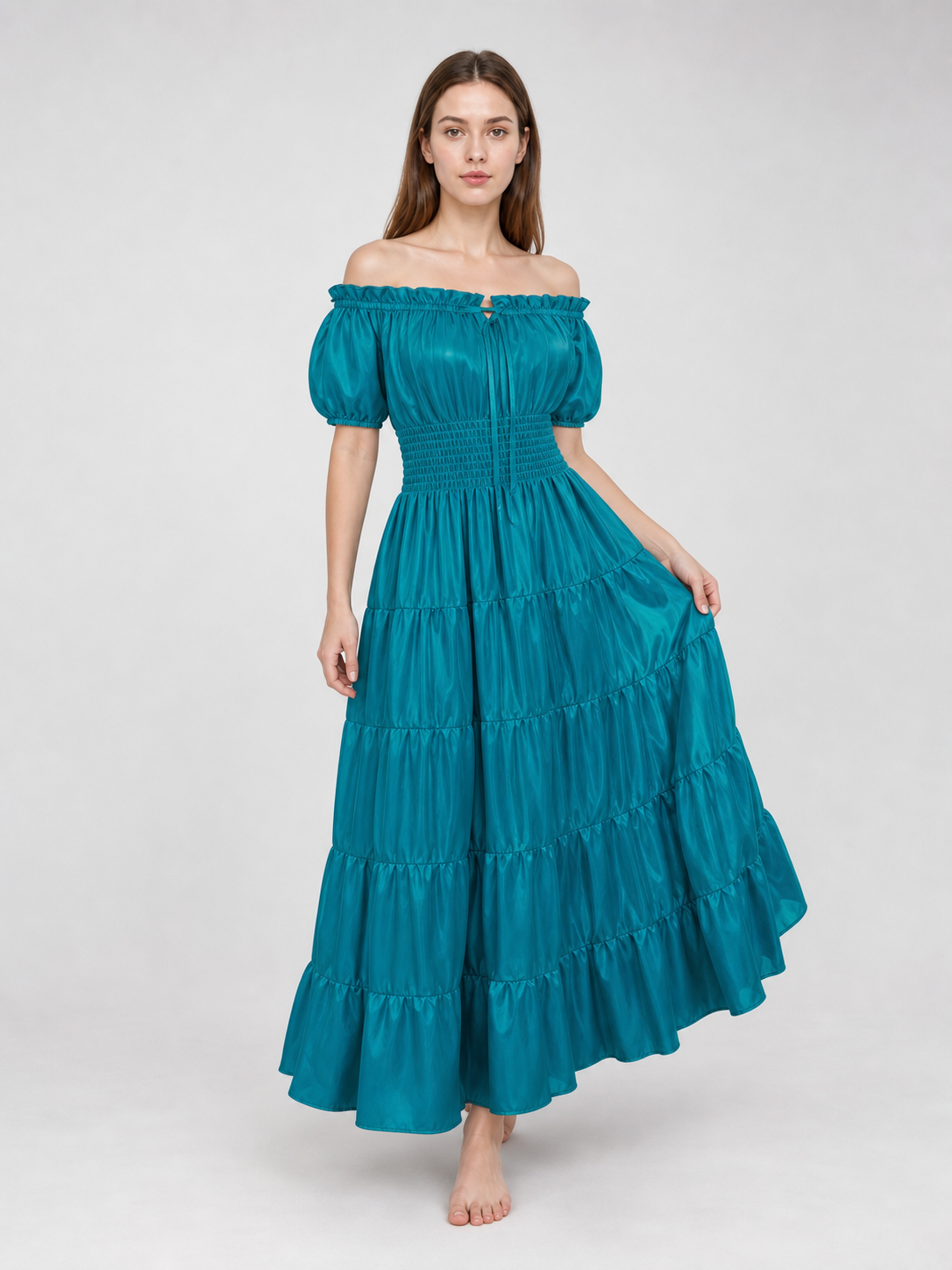 Teal glossy maxi dress on a model lifting the skirt to show its wide, flowing shape and multiple gathered tiers