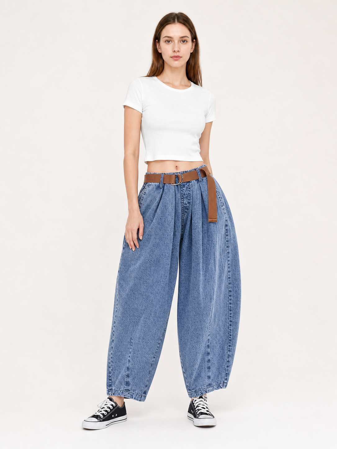 Full-body front view of blue denim pants paired with a white cropped shirt, showing wide legs, side pockets, and a brown belt