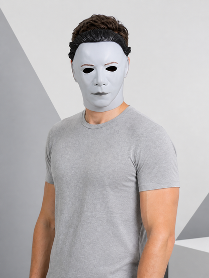 White face mask with black molded hair worn by a man in a gray shirt, shown from the front against a geometric background