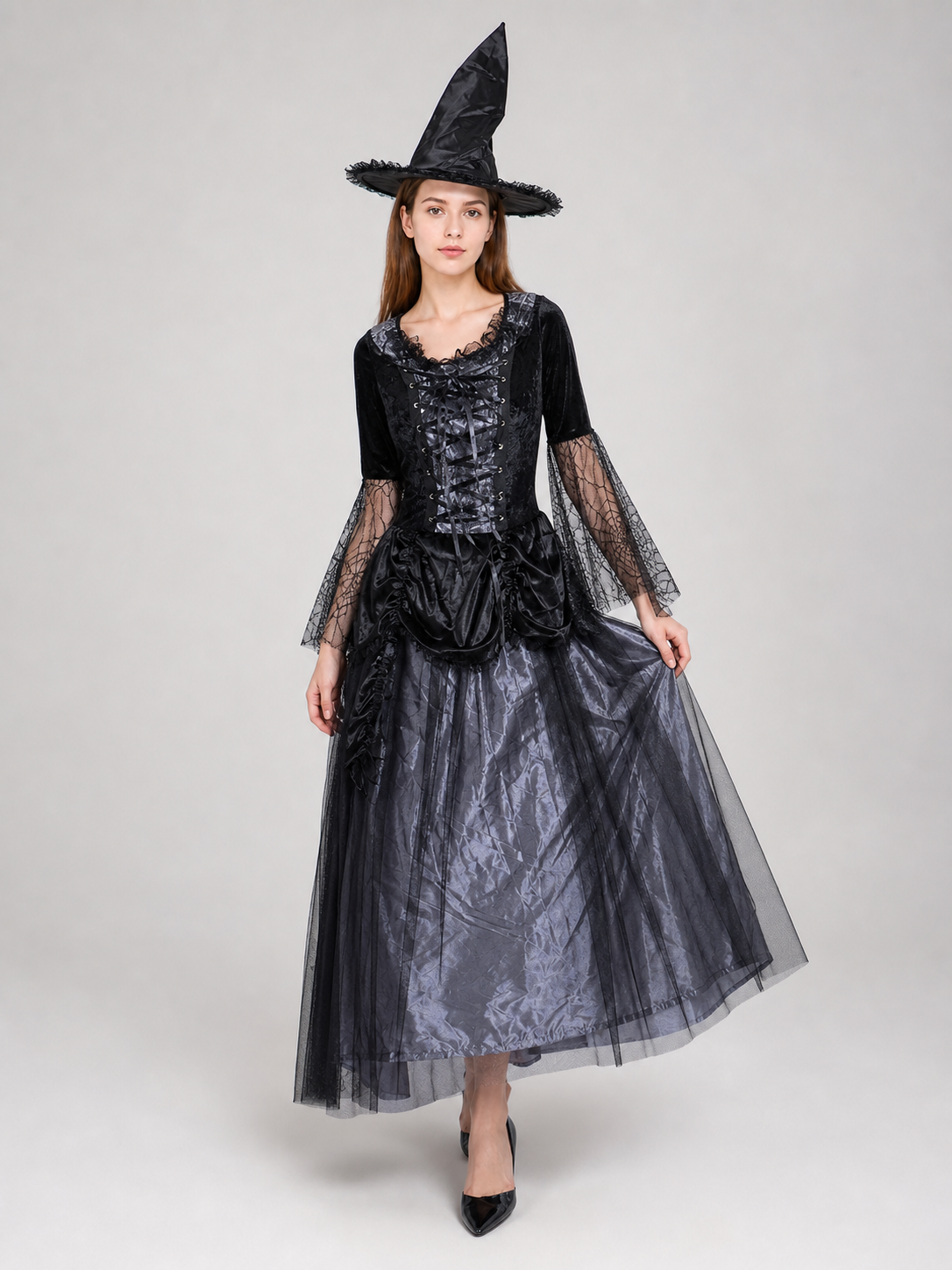 Gothic-style witch costume dress with hat for themed events. The design is mainly black and dark gray, with patterned textured fabric and sheer black accents. The look is centered on a long dress with a fitted lace-up corset, a ruffled neck