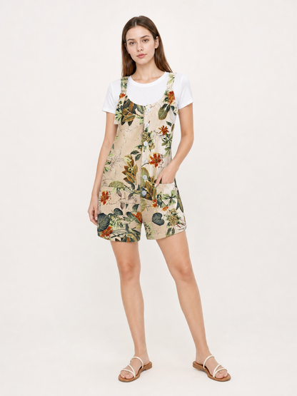 Model wearing a beige floral romper over a white T-shirt with white strappy sandals