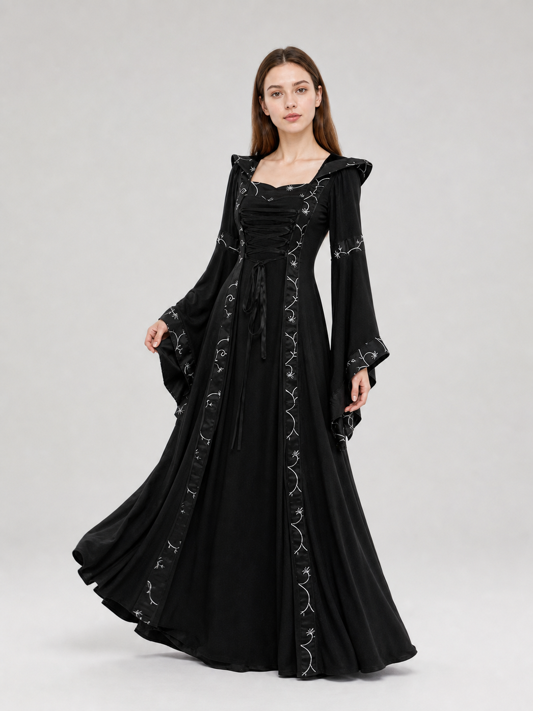 The dress is designed in a gothic style with elements of Victorian aesthetics. The model features a flared silhouette, a square neckline, and long sleeves with flared cuffs. The bodice is decorated with gathers that emphasize the garment’s 