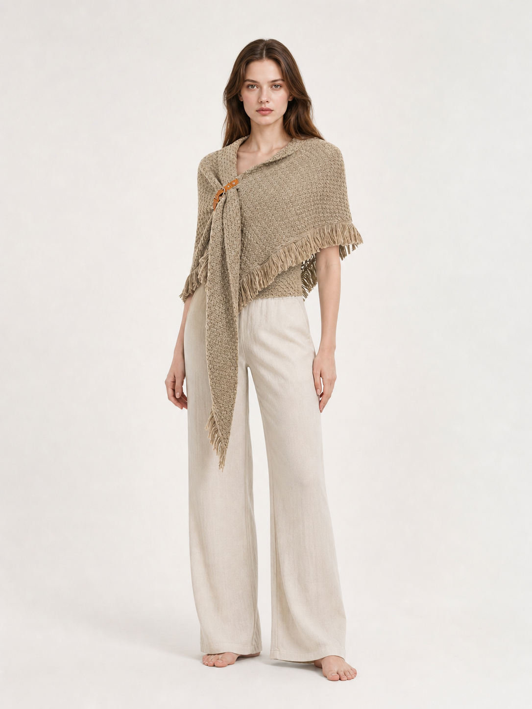 Back view of a beige woven cape on a model wearing black leggings, showing the triangular drape and fringed hem