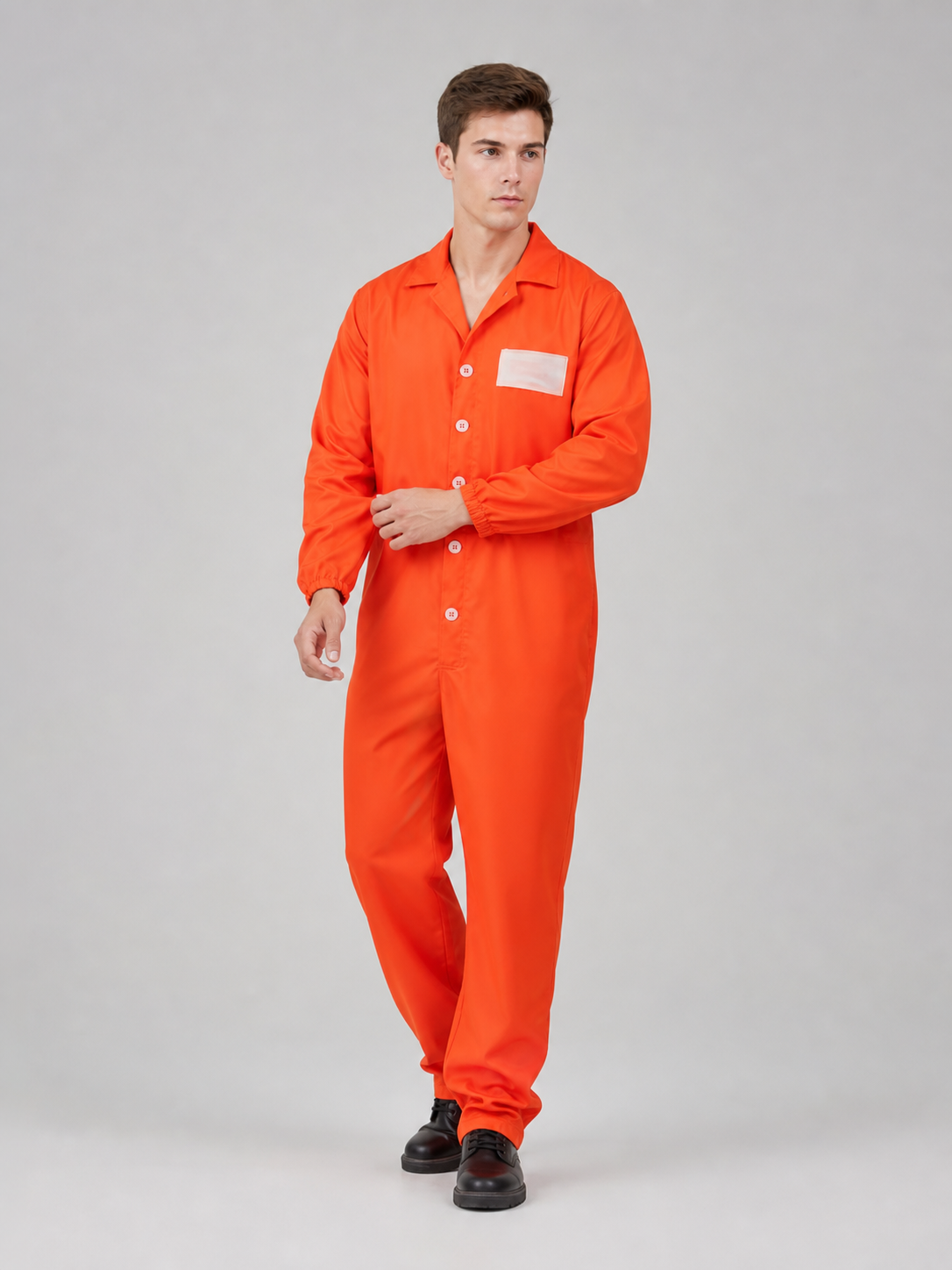Orange coverall with a smooth fabric look, collared button front, chest patch, and elastic cuffs, shown full-body on a model standing at an angle