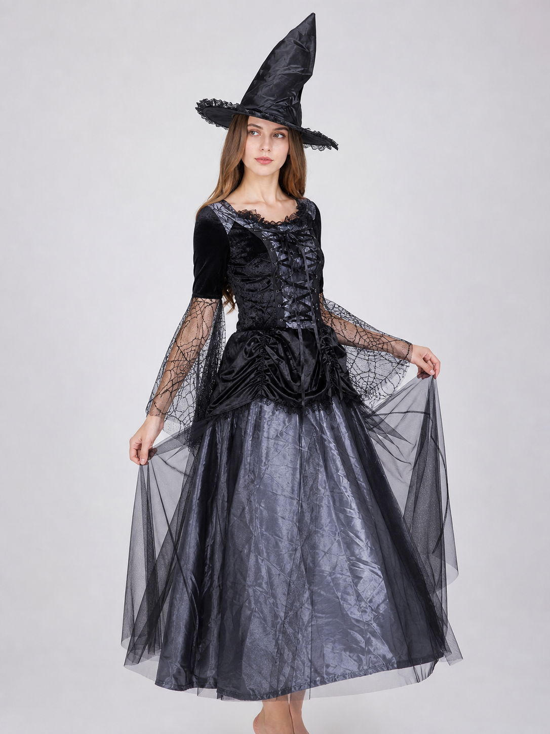 Gothic-style witch costume dress with hat for themed events. The design is mainly black and dark gray, with patterned textured fabric and sheer black accents. The look is centered on a long dress with a fitted lace-up corset, a ruffled neck