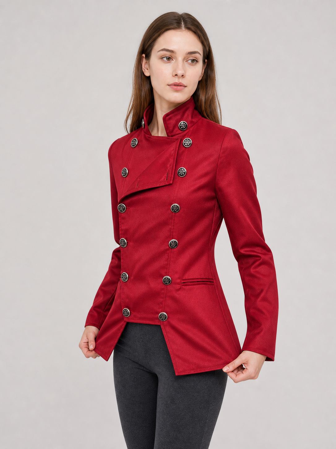 The jacket is presented in a vintage red color and designed in a military style with elements of Gothic aesthetics. The model features a distinctive front construction with a diagonal wrap, giving the garment a bold character. A double row 