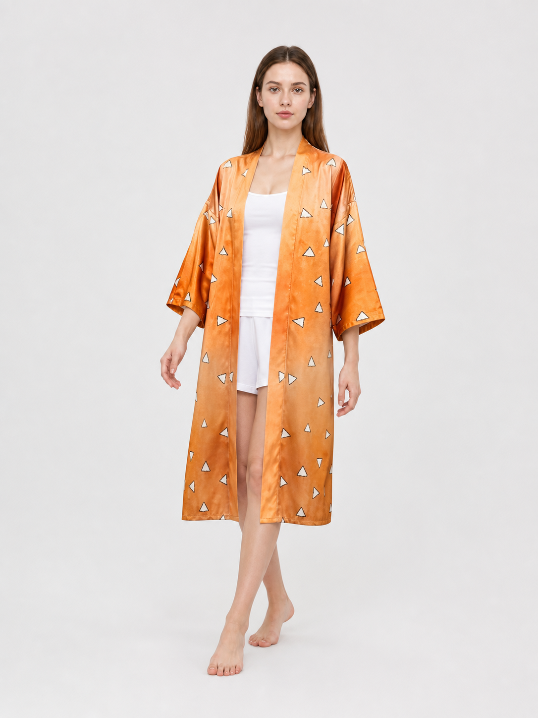 Front view of a model walking in an orange satin-look robe with wide sleeves and white triangle pattern