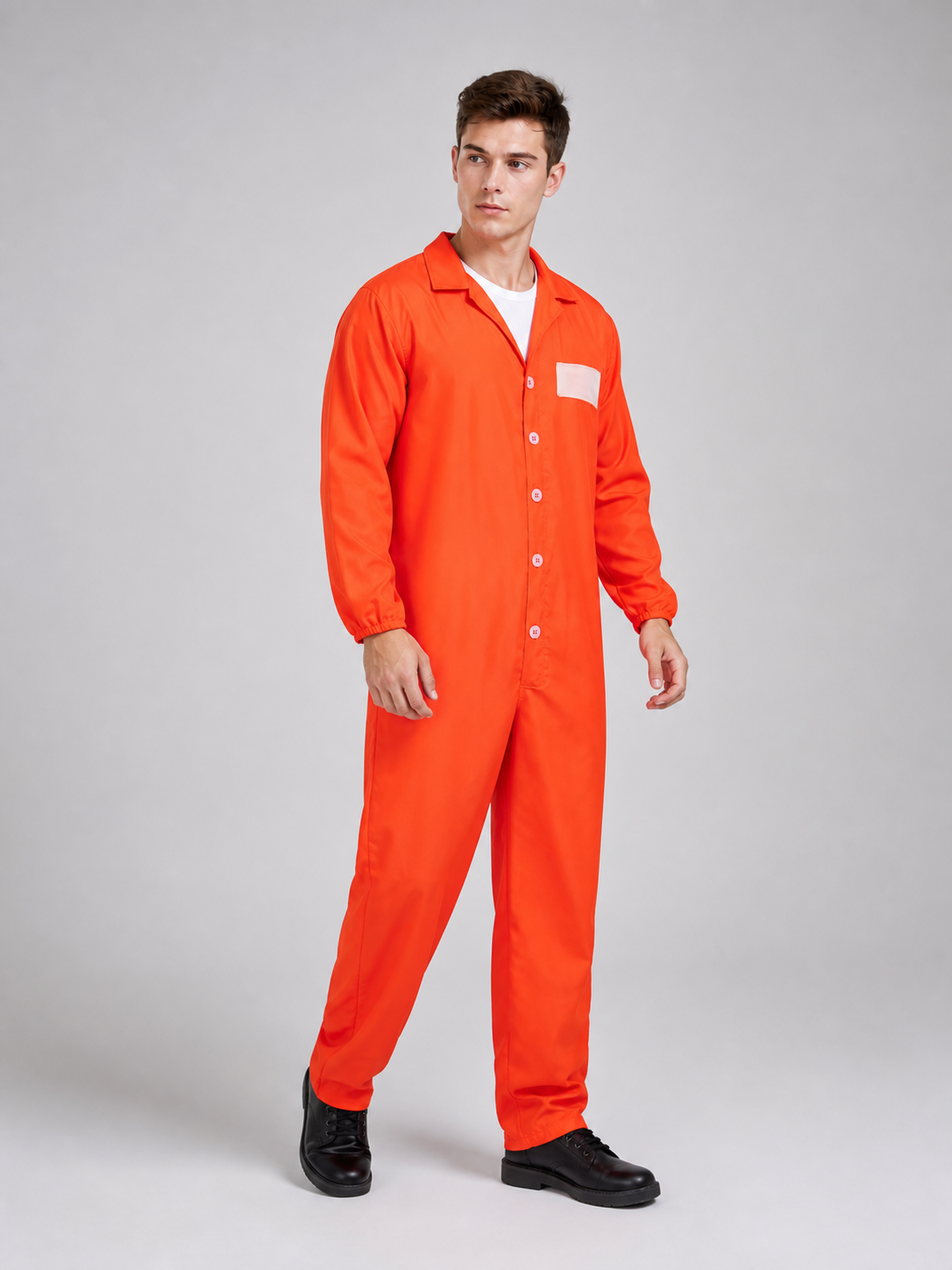 Orange coverall with a smooth fabric look, collared button front, chest patch, and elastic cuffs, shown full-body in side view on a barefoot model
