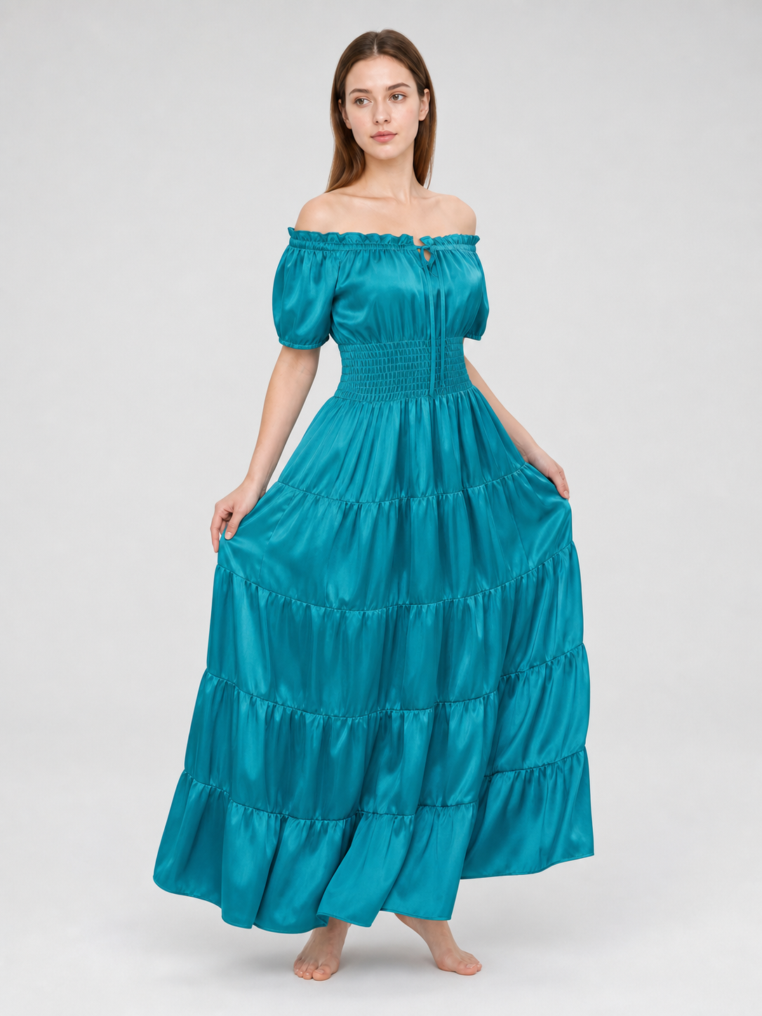 Teal satin-look maxi dress on a model holding both sides of the skirt, showing the full gathered volume and tiered construction