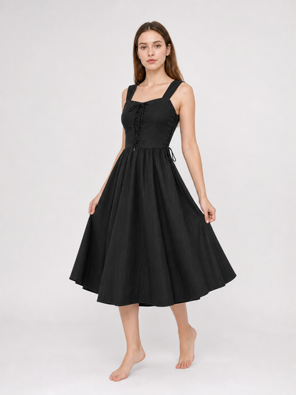 Black midi dress shown at an angle on a model, with a square neckline, lace-up bodice, side waist ties, and a wide flowing skirt