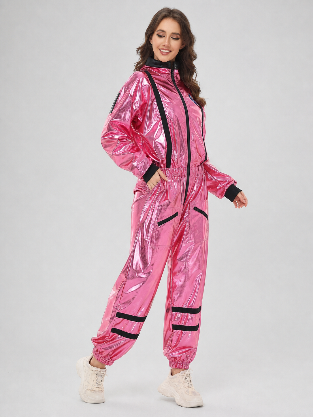 The pink NASA astronaut costume is designed as a one-piece jumpsuit with long sleeves, a stand-up collar, and a central zip closure. The model is pink with black decorative elements: a vertical stripe on the front, zippered side pockets, ho