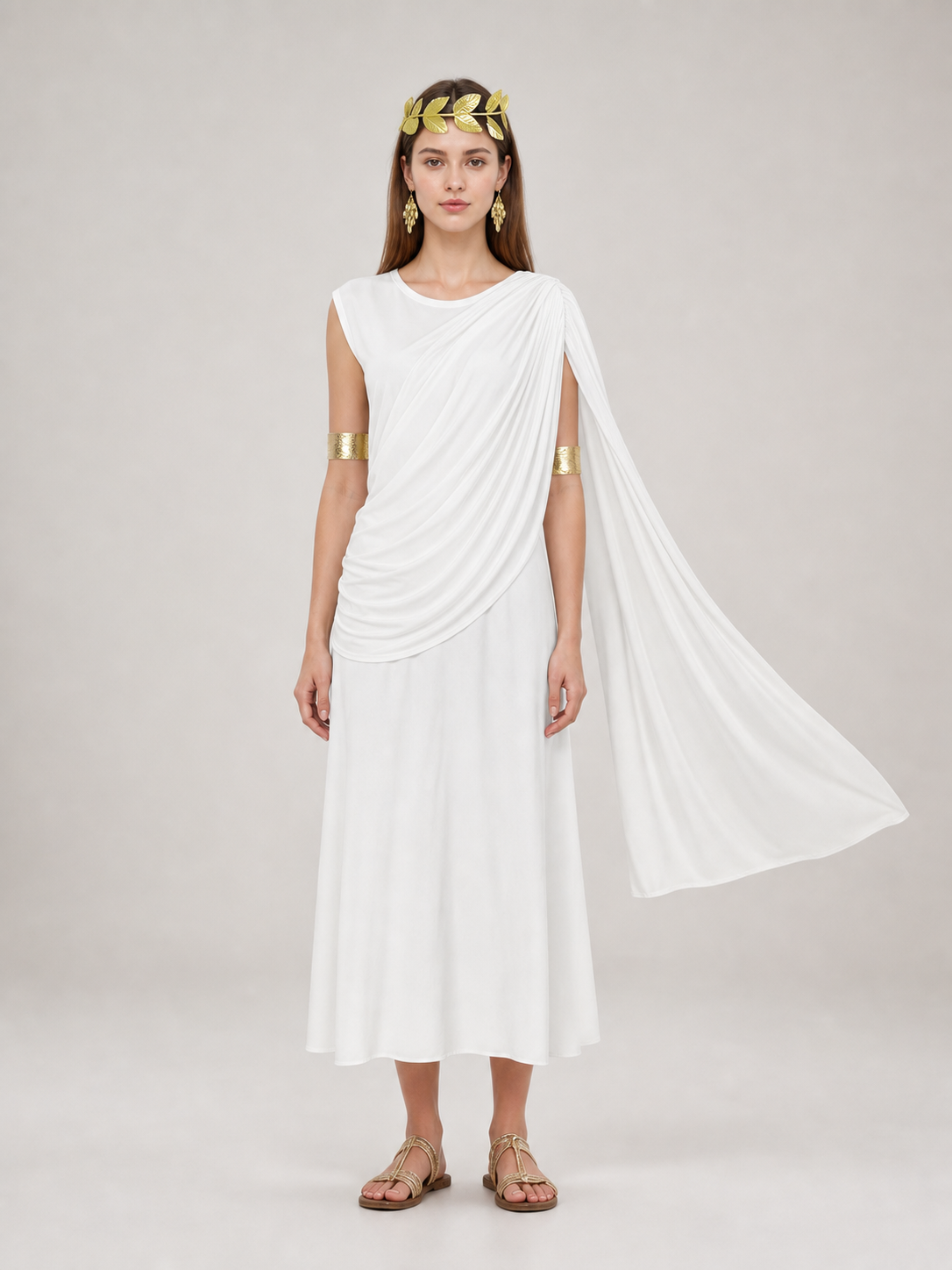 Full-body model wearing a white draped dress with a flowing shoulder train and gold accessories in a warmly lit interior