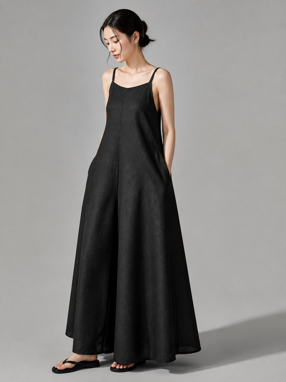 Loose black bib overalls with thin shoulder straps. The design features a simple solid black color and a straight, wide-leg silhouette with long pant legs. The upper portion is styled as a bib, while the thin shoulder straps complement the 