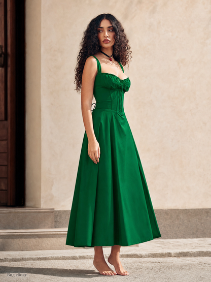 Green strappy dress with a gathered bodice and long skirt. The dress features a square neckline, exposed shoulders, and thin straps. The front of the bodice includes gathered details and ties that serve as a noticeable design element. The f