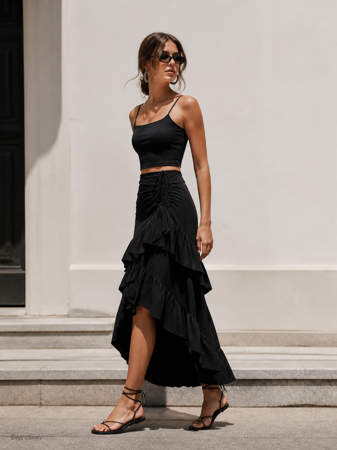 Black skirt in black with an asymmetrical silhouette and a layered tiered hem. The main visual feature of the style is a cascade of ruffles arranged in layers, creating a draped, stepped structure. The hem is finished asymmetrically, with l