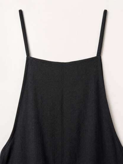 Loose black bib overalls with thin shoulder straps. The design features a simple solid black color and a straight, wide-leg silhouette with long pant legs. The upper portion is styled as a bib, while the thin shoulder straps complement the 