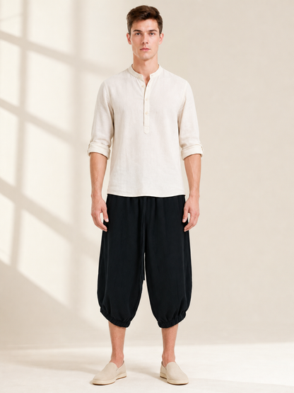 Front view of black cropped pants with loose legs and elastic ankle cuffs, worn with a light shirt and slip-on shoes